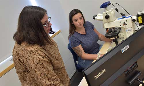 Associate Professor of Biology Dr. Kristin Giamanco assists a student in the Microscopy Lab.