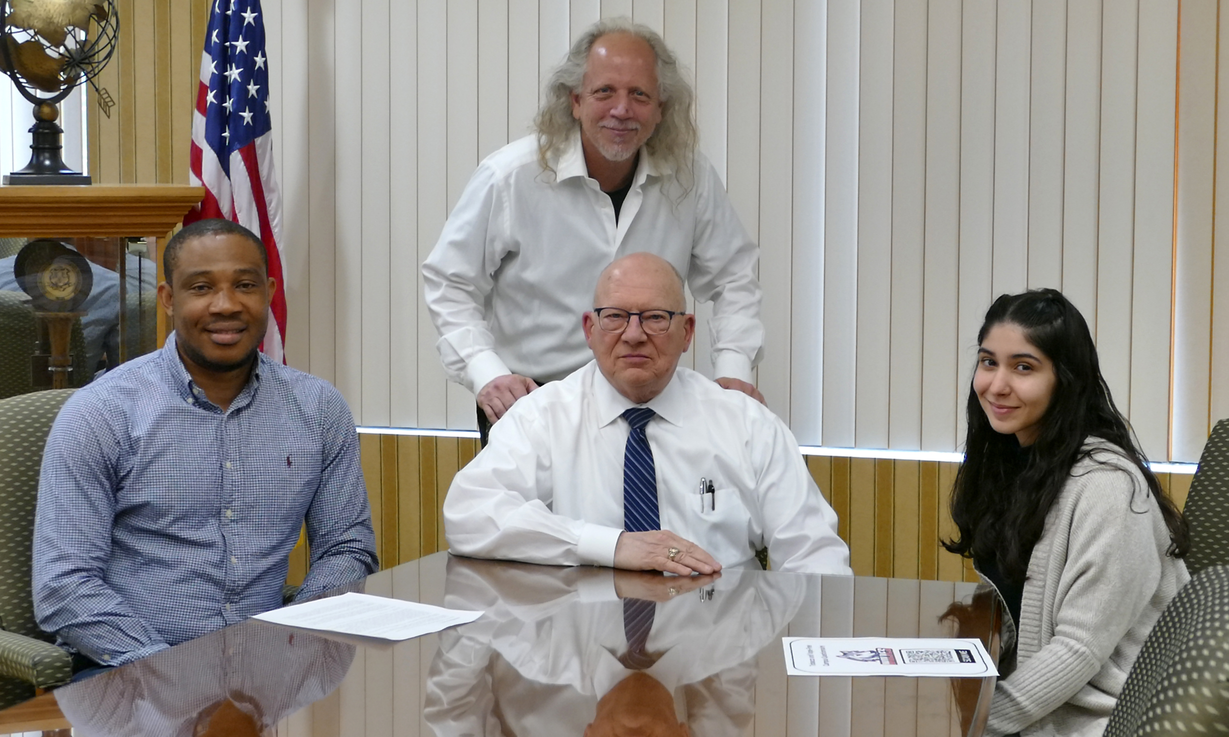 (l-r, seated): Uche Aja, student Campus Leader, Interim President Dr. Paul B. Beran and Keithsany Valentin, student Campus Leader, at the signing ceremony for Western Connecticut State University’s expanded Tobacco and Vape-Free Policy, along with Dr. Jeffrey Schlicht (standing), WCSU policy adviser and HPX professor.